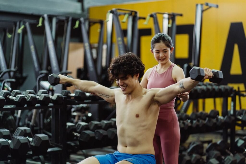 Dos personas realizando ejercicios de fuerza con mancuernas en un gimnasio