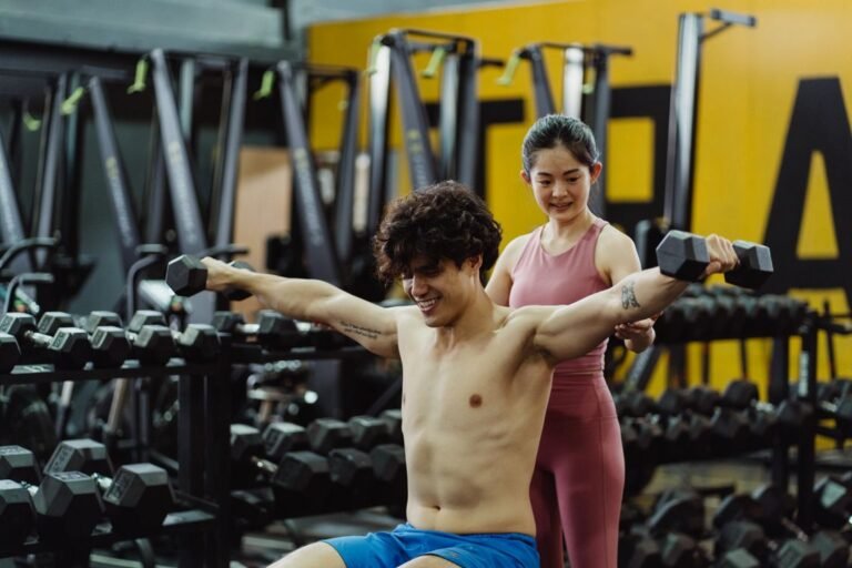 Hombre y mujer entrenando fuerza con mancuernas en un gimnasio
