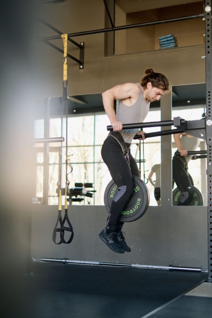Hombre fuerte realizando dominadas lastradas en un gimnasio